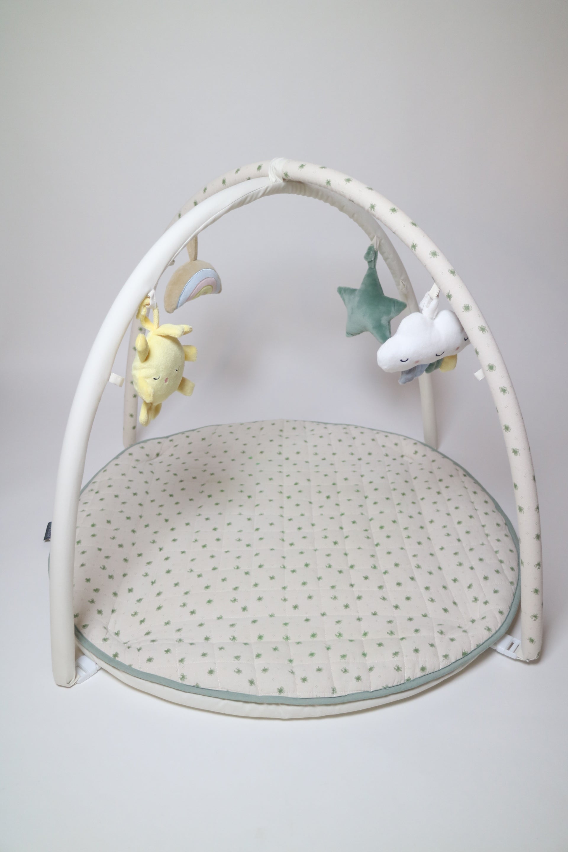 Babygym i modell Meadow från Vinter &amp; Bloom. Den quiltade mattan är vit med gröna blommor/klöver och kan även användas som lekmatta genom att ta av bågarna. 