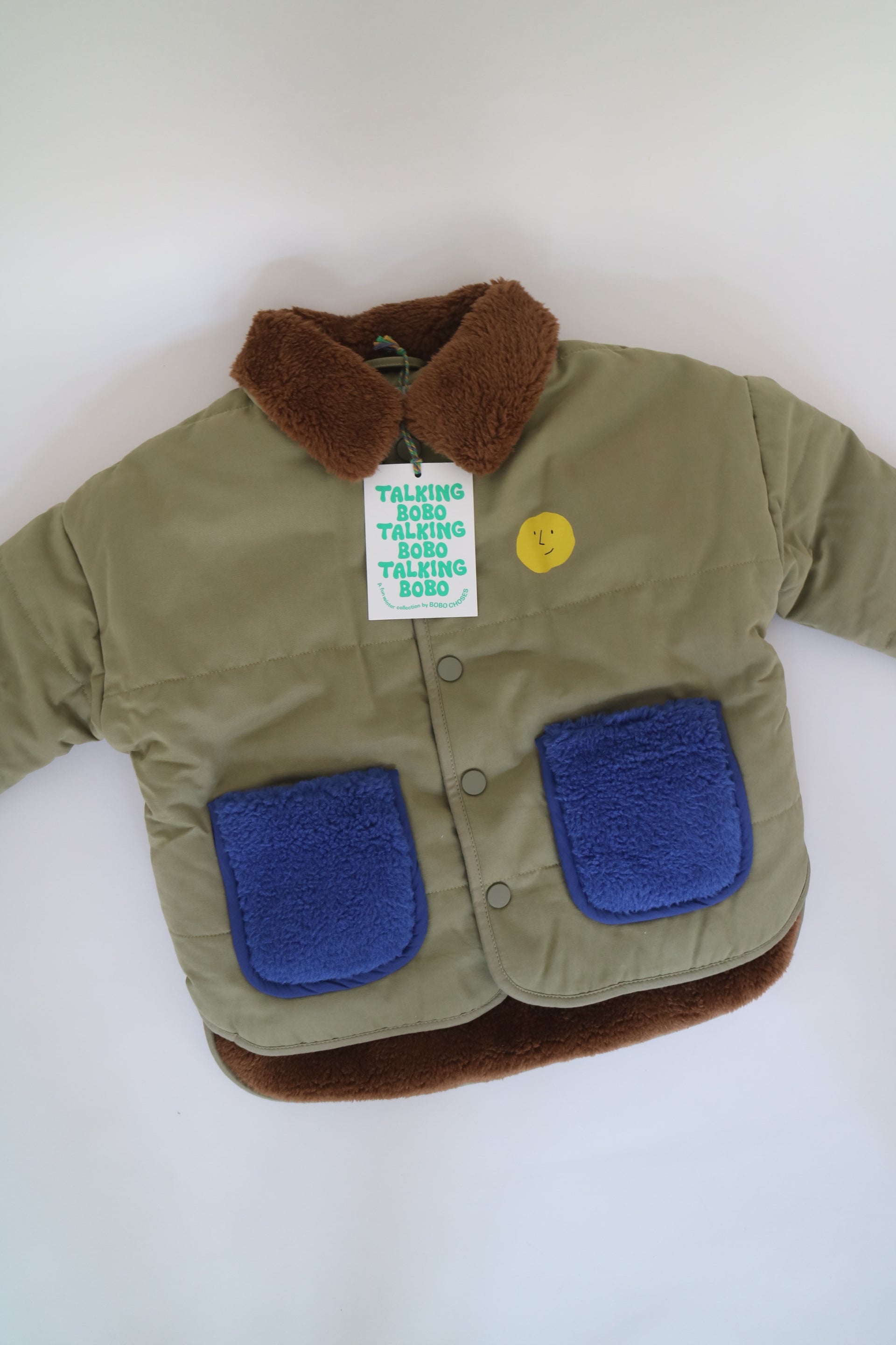 Fodrad jacka i ljus militärgrön färg med kornblåa fickor och brun krage i teddy-material från Bobo Choses, modell Face Multicolor Jacket.5