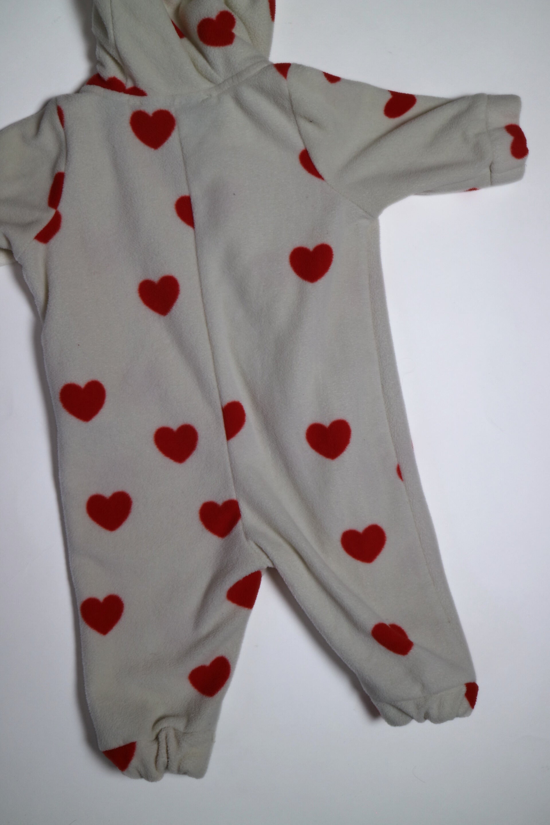 Fleece-onesie med heltäckande Hearts-print tillverkad i 100 % återvunnen polyester, fodrad med fleece, från Mini Rodini. Onesien har dragkedja från hals till benslut och Mini Rodinis klassiska Panther-märke framtill. 