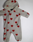 Fleece-onesie med heltäckande Hearts-print tillverkad i 100 % återvunnen polyester, fodrad med fleece, från Mini Rodini. Onesien har dragkedja från hals till benslut och Mini Rodinis klassiska Panther-märke framtill. 