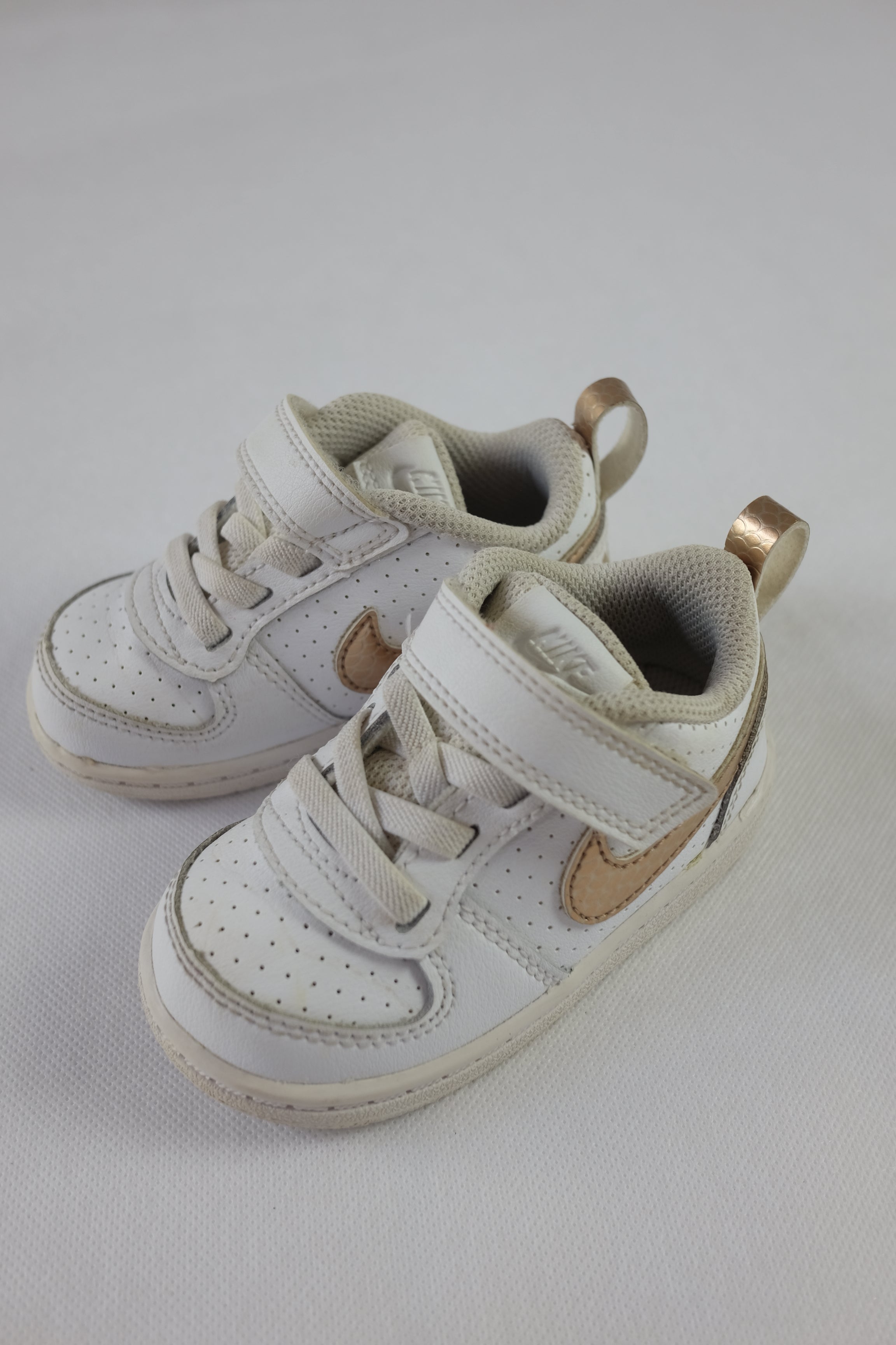 Sneakers från Nike i barnstorlek. Vita, med Nike-logotypen i guld. 