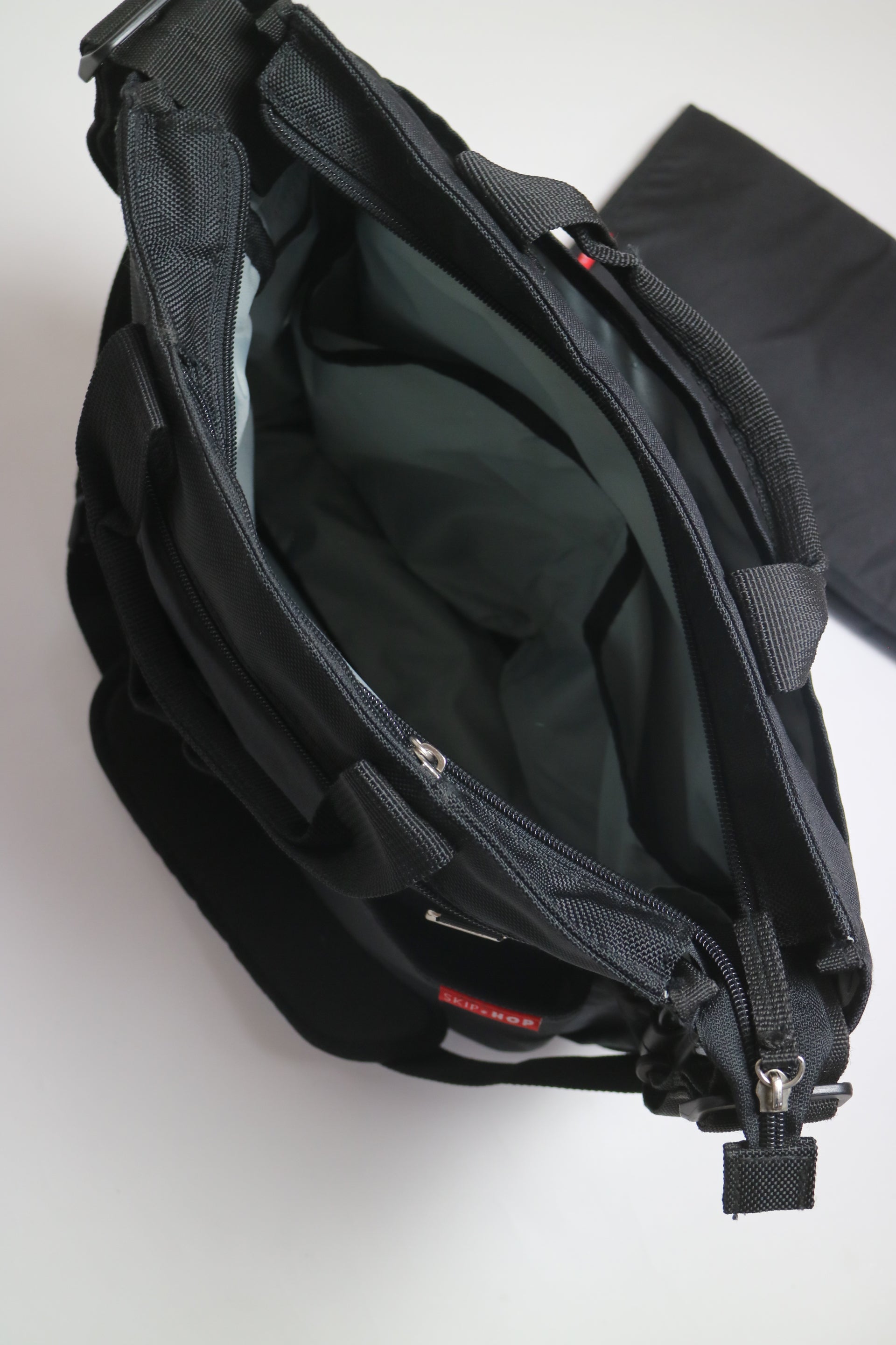 Praktiska skötväskan Skip Hops Duo Signature i svart, som kan bäras både i handen och över axeln. Väskan har både sidofack och inner- och ytterfickor, för bra förvaring. Flera av de stora facken är även säkrade med blixtlås.