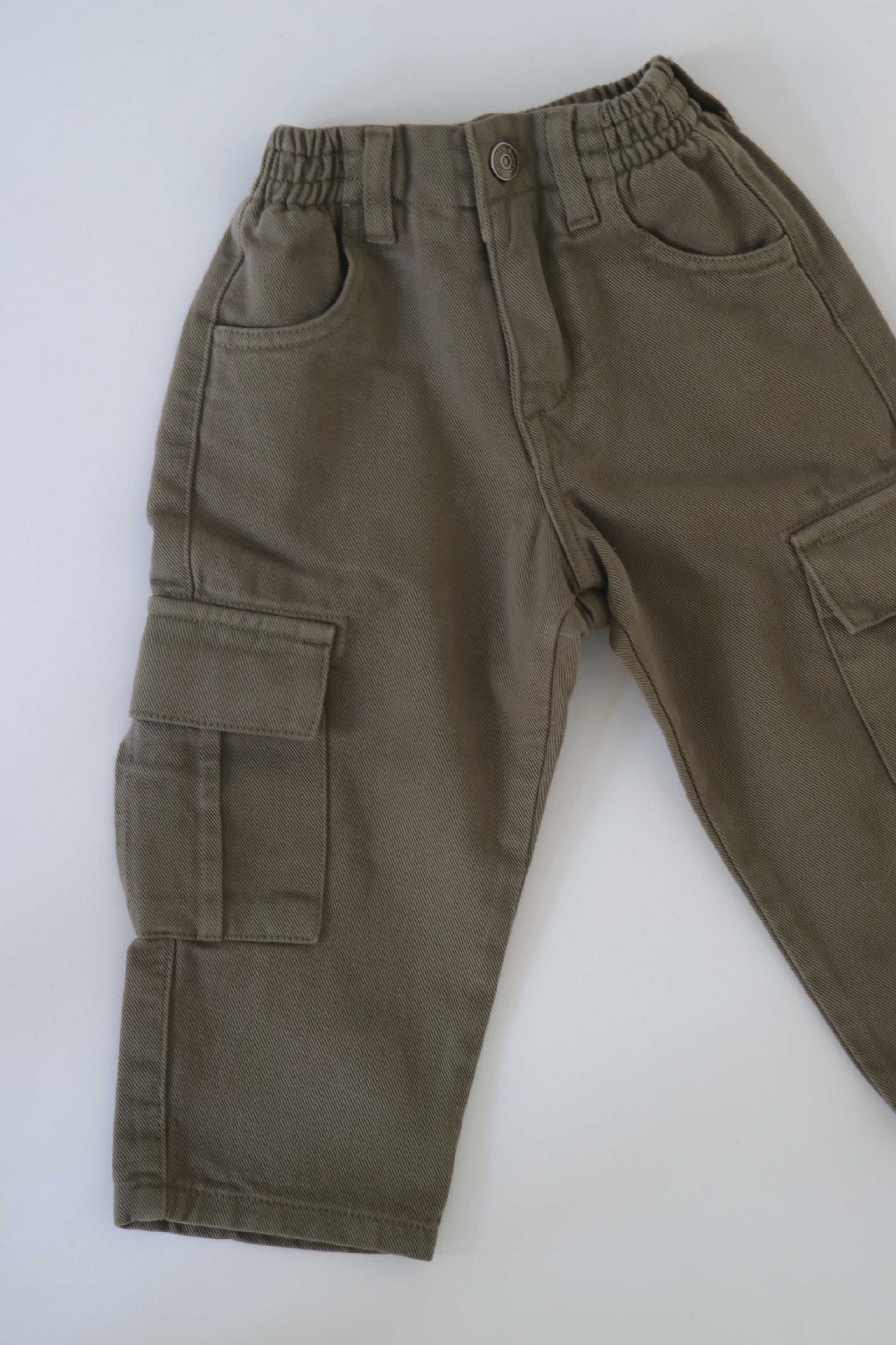 Khakigröna byxor från The New Society av modell Vincent Pant Dried Herb. Cargobyxor med fickor framtill, baktill och längs byxbenen. Byxorna är elastiska i midjan med knapp framtill. Helt nya med prislapp kvar.&nbsp;