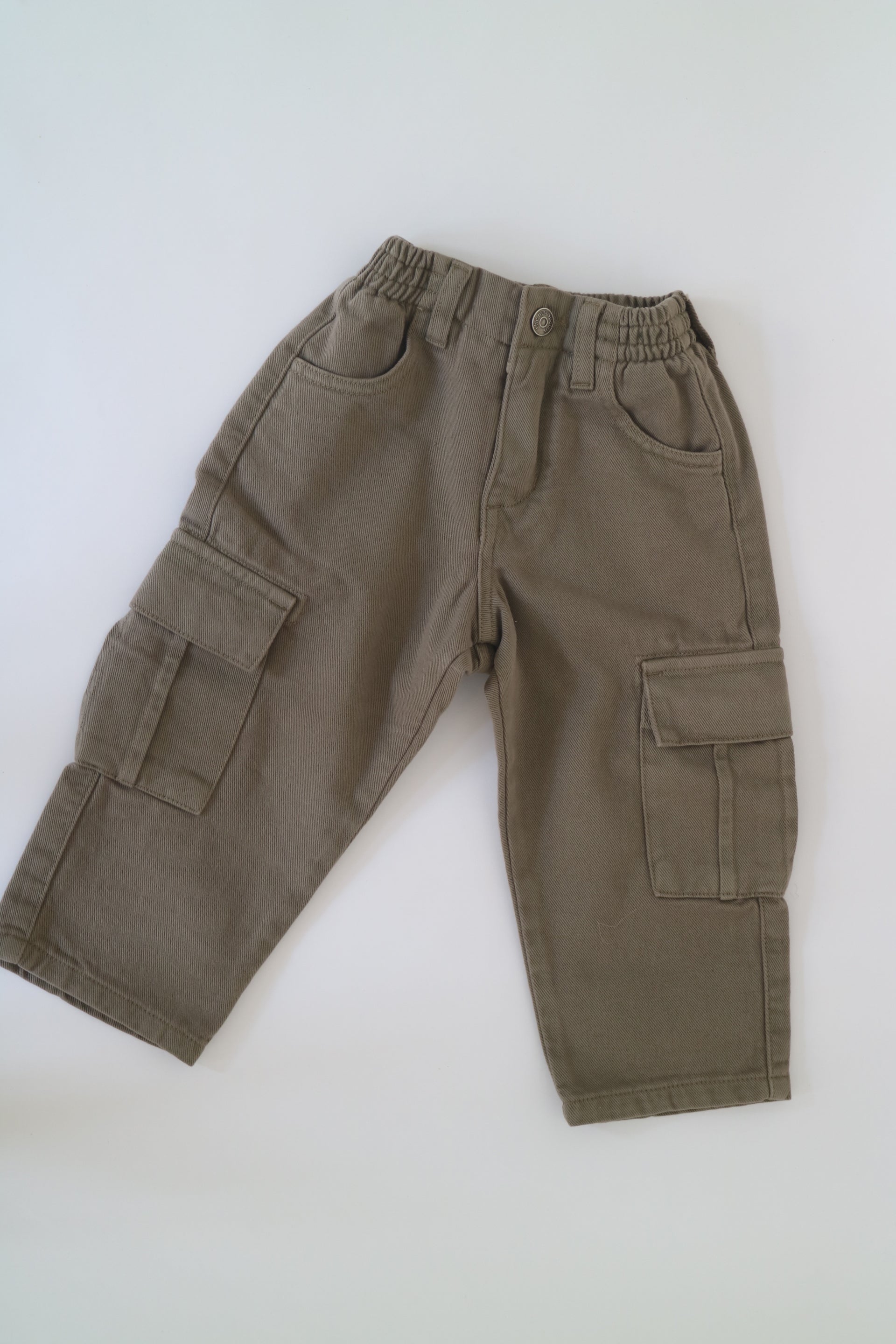 Khakigröna byxor från The New Society av modell Vincent Pant Dried Herb. Cargobyxor med fickor framtill, baktill och längs byxbenen. Byxorna är elastiska i midjan med knapp framtill. Helt nya med prislapp kvar.&nbsp;