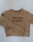 Beige sweatshirt i beige från The New Society, färg Camel. Logo med The New Society i teddy material.&nbsp;