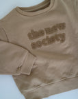 Beige sweatshirt i beige från The New Society, färg Camel. Logo med The New Society i teddy material.&nbsp;