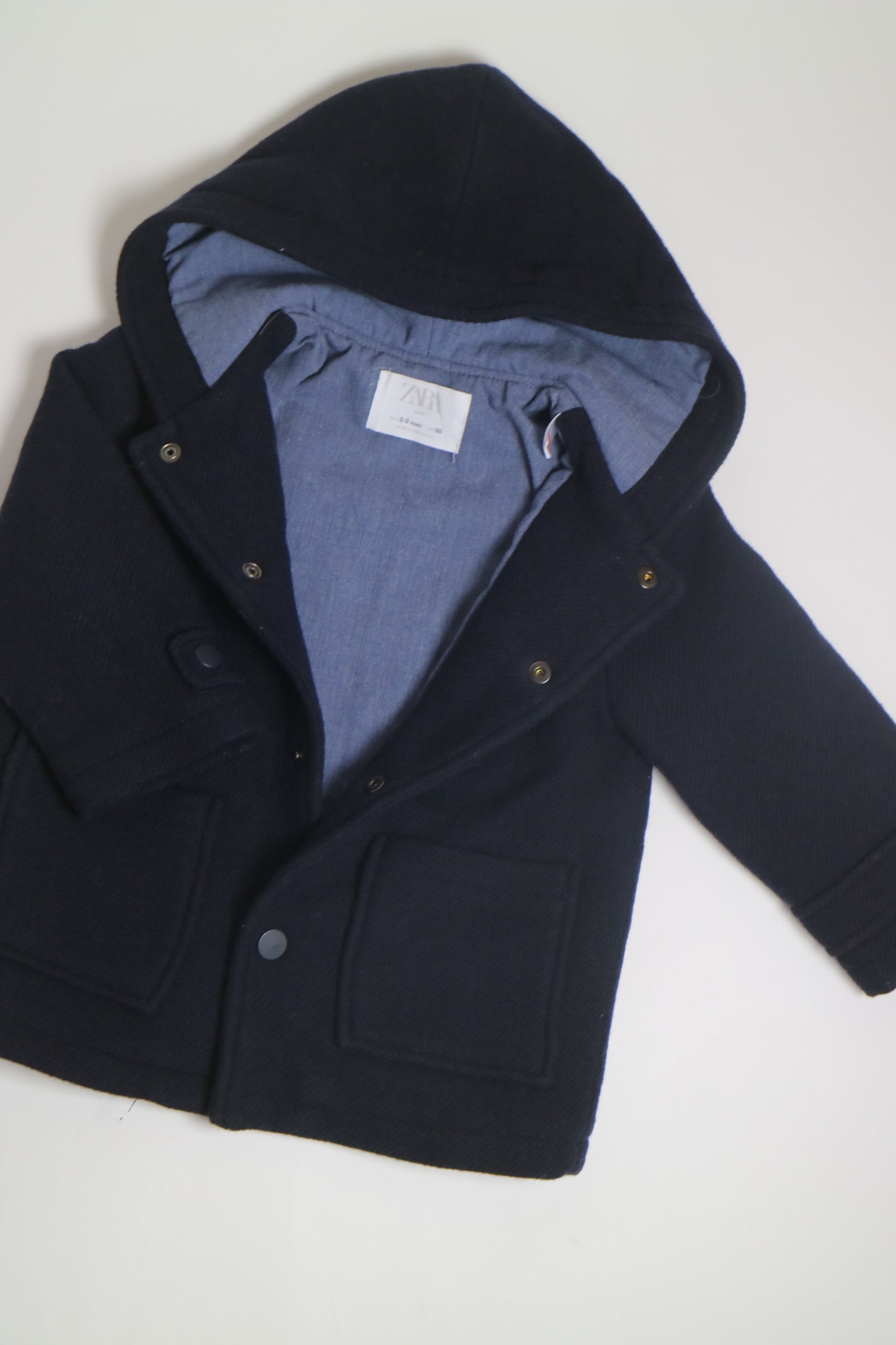 Mörkblå jacka från Zara med luva, tryckknappar och stora fickor framtill.